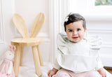 baby girl sitting and wearing a sage green ruffle baby bib