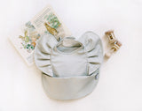 sage green ruffle baby bib with baby book and rattles