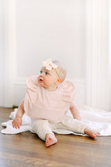 baby girl sitting and wearing a pink ruffle angel bib