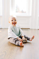 Baby boy staring up at camera wearing a birch green silicone baby bib